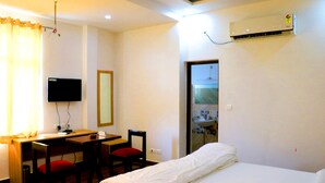 Habitación de hotel con cama, escritorio, silla, televisión y aire acondicionado.