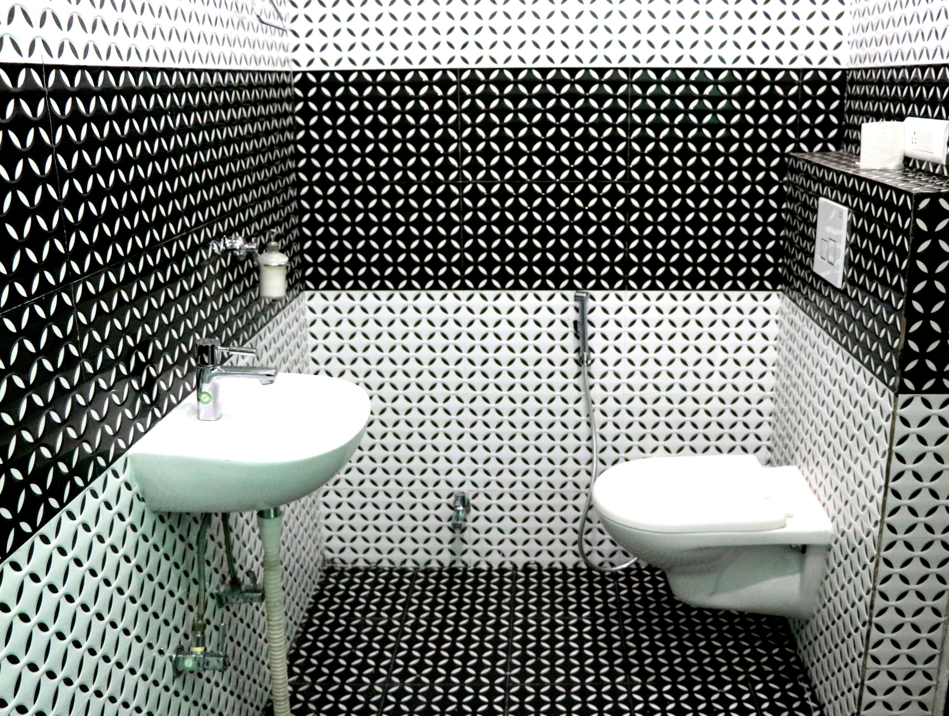 Ein Badezimmer mit einem schwarz-weißen geometrischen Fliesenmuster, einem weißen Waschbecken und einer Toilette.
