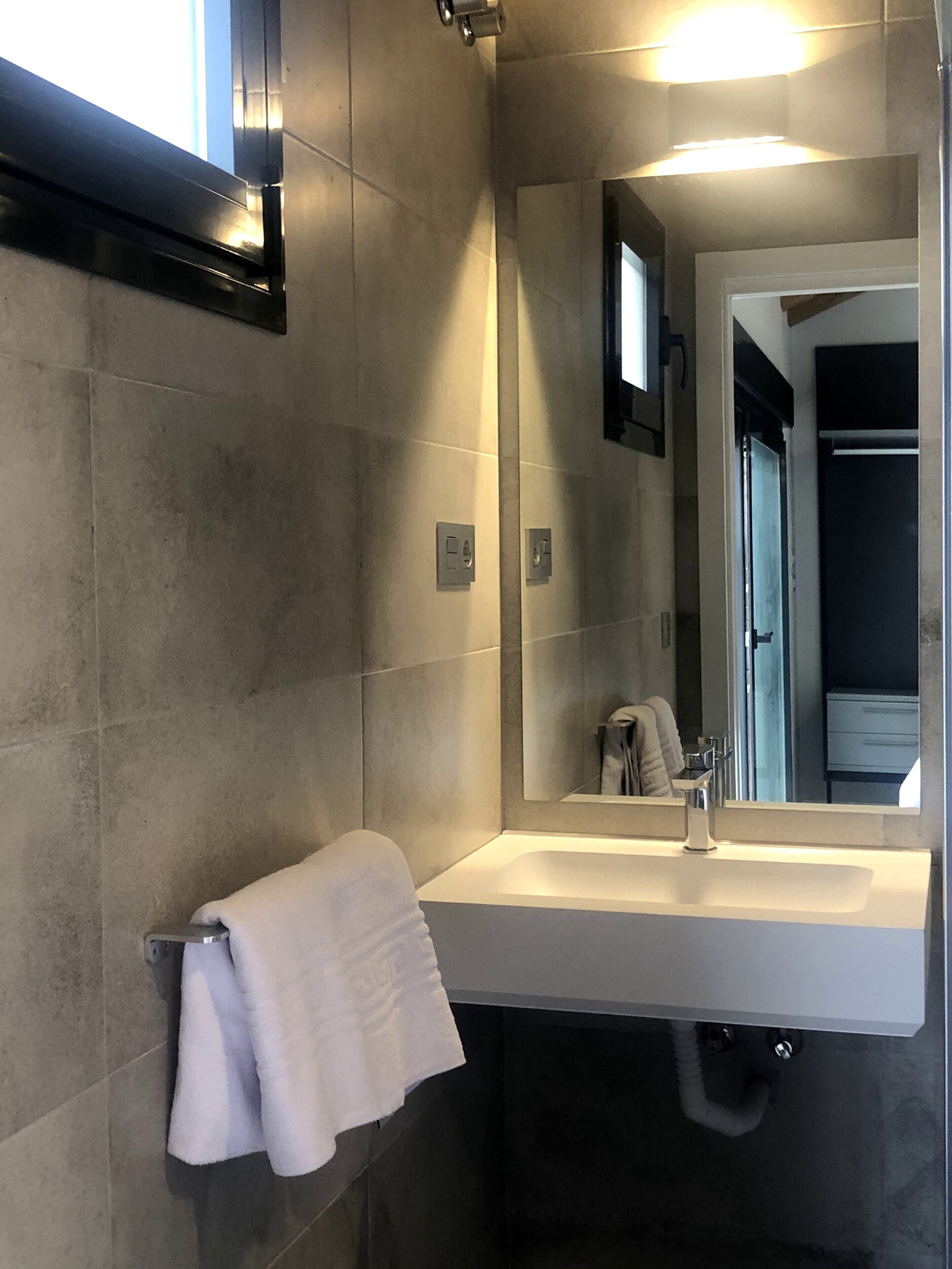 Een moderne badkamer met een grote spiegel, een wit wastafelmeubel en een handdoekrek.
