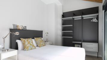 A modern bedroom with a bed, bedside tables, a wardrobe, and a hanging clothes rack.