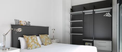 A modern bedroom with a bed, bedside tables, a wardrobe, and a hanging clothes rack.