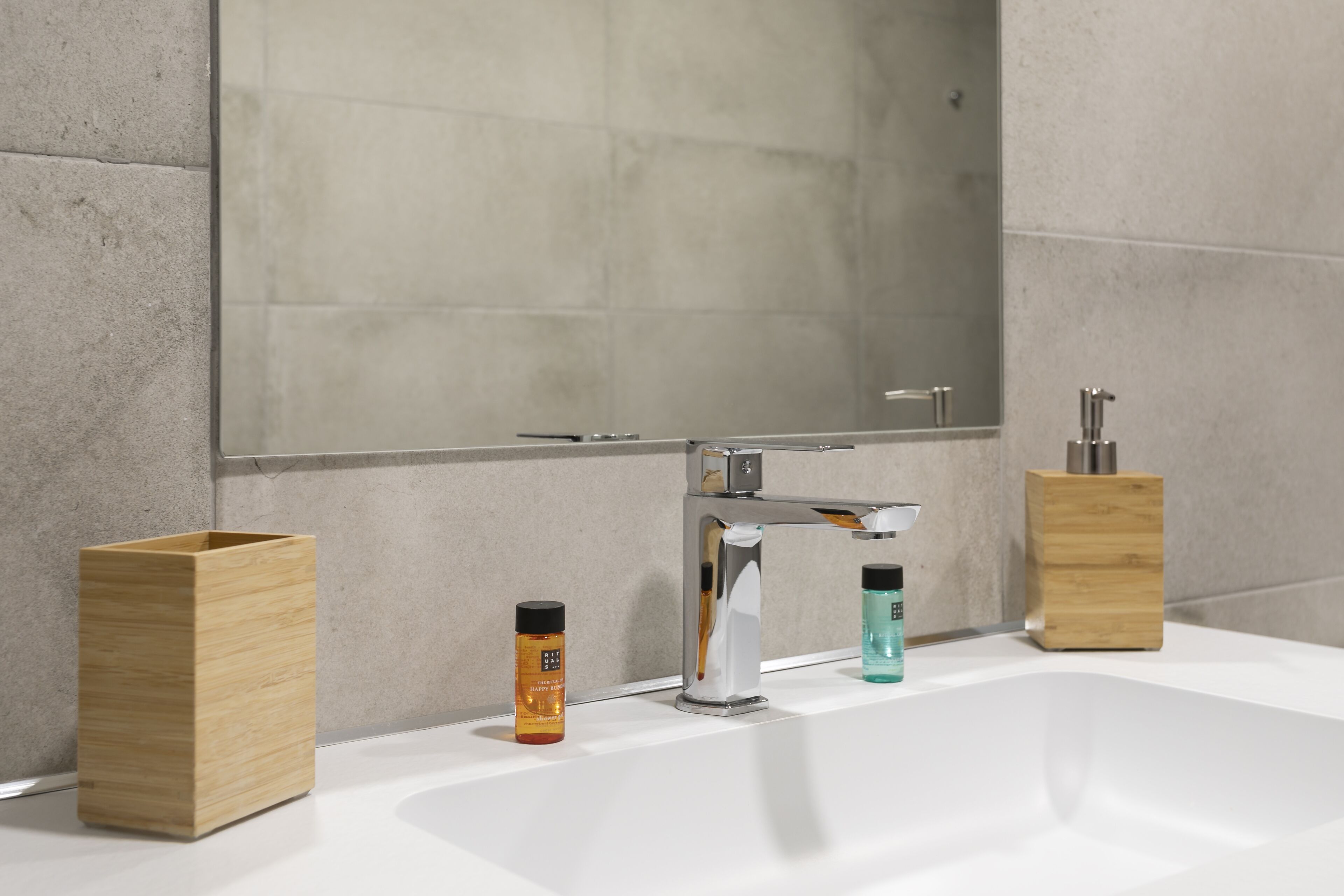 Un bagno moderno con uno specchio grande, un lavandino bianco e due contenitori in legno.