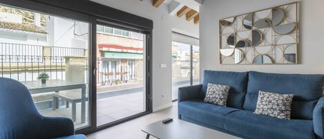 A modern living room with a blue sofa, a patterned armchair, and a coffee table.