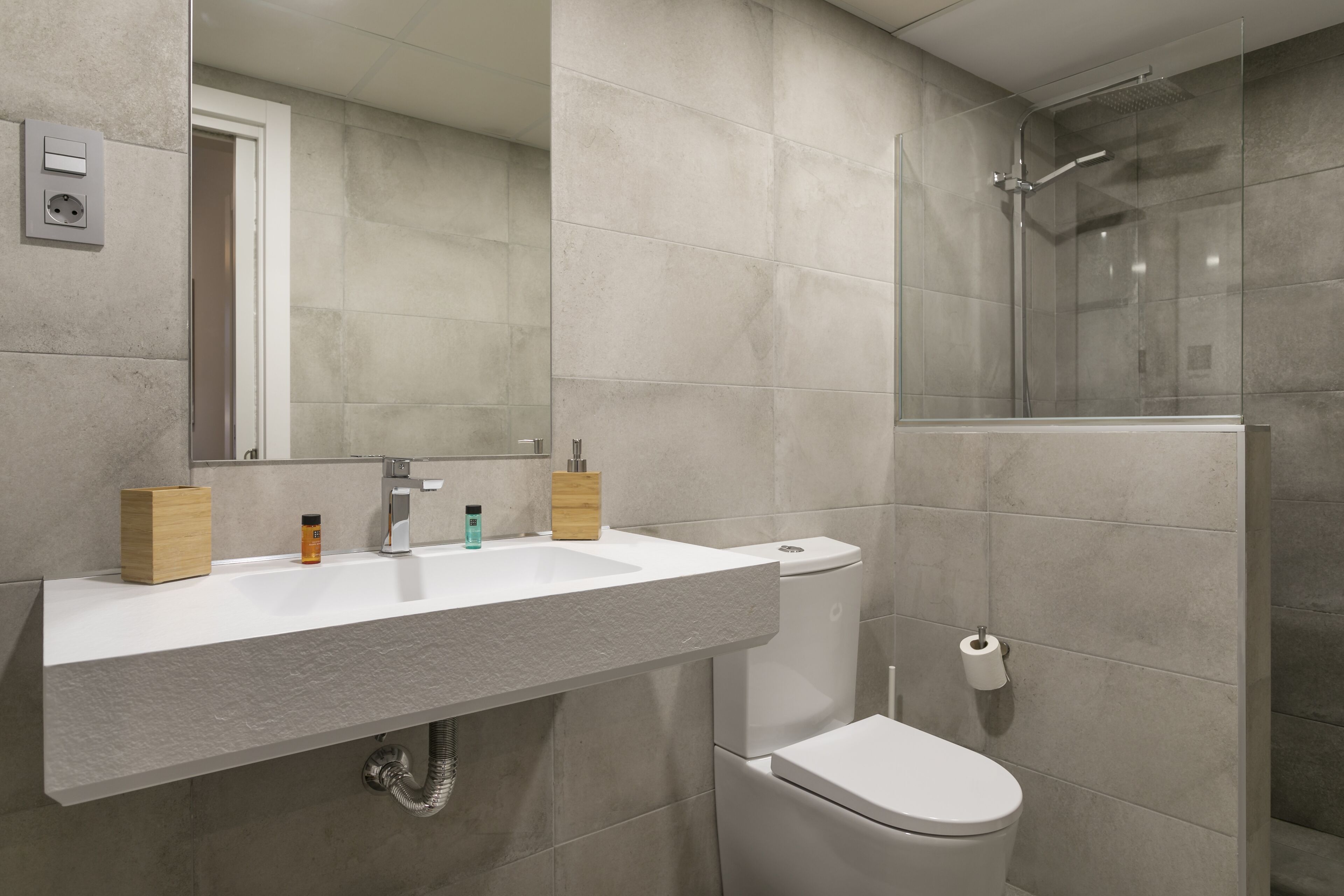 A modern bathroom with a large sink, toilet, and glass-enclosed shower.