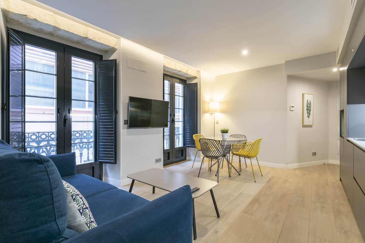 A modern living room with a sofa, a coffee table, and a dining area with chairs.