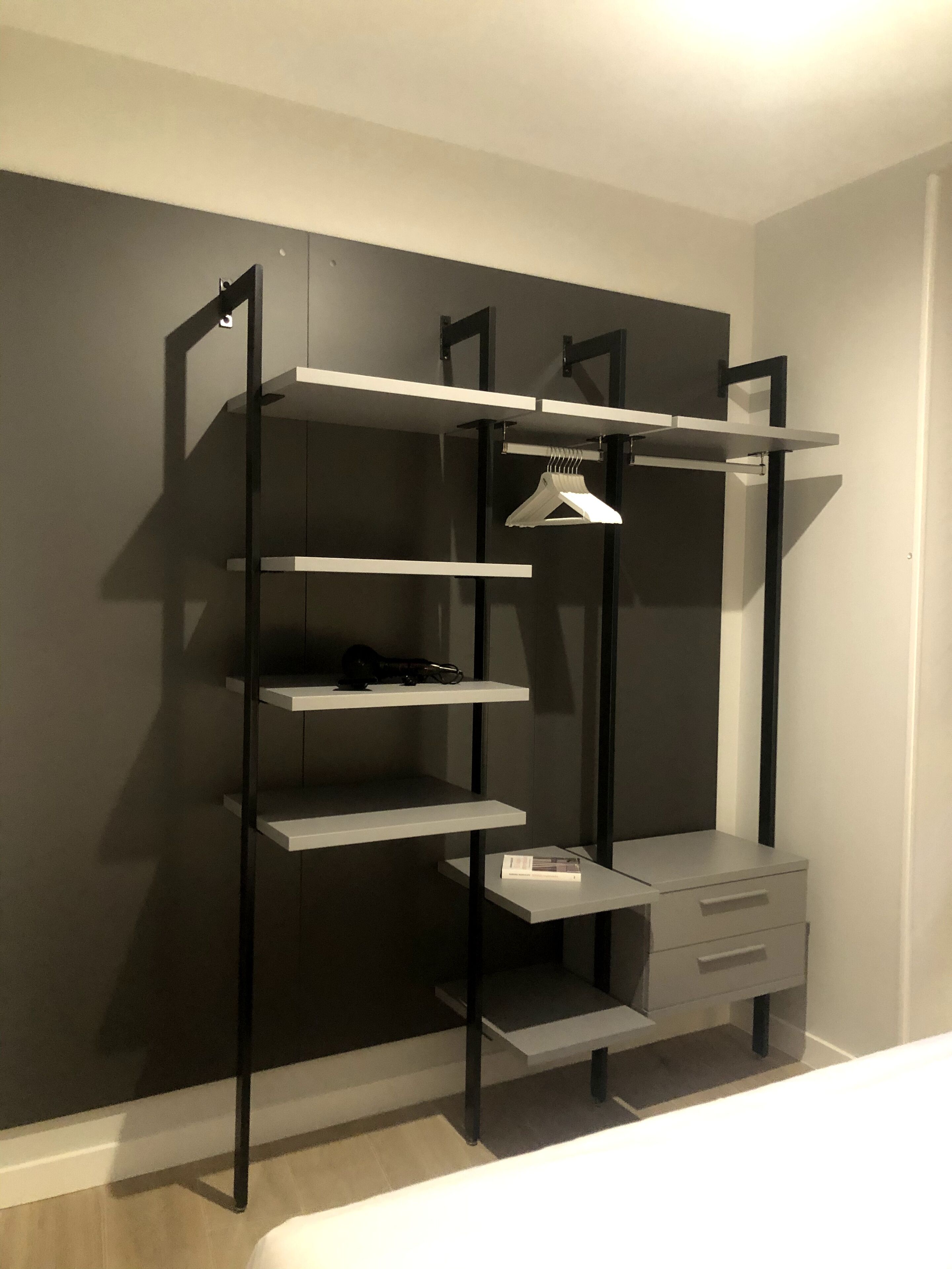Un armario moderno y minimalista con varios estantes y una barra para colgar, que destaca por su diseño elegante y cajones integrados.