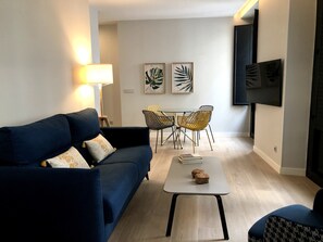 Un salon moderne avec un canapé bleu foncé, une petite table basse et un coin repas comprenant une table et des chaises.
