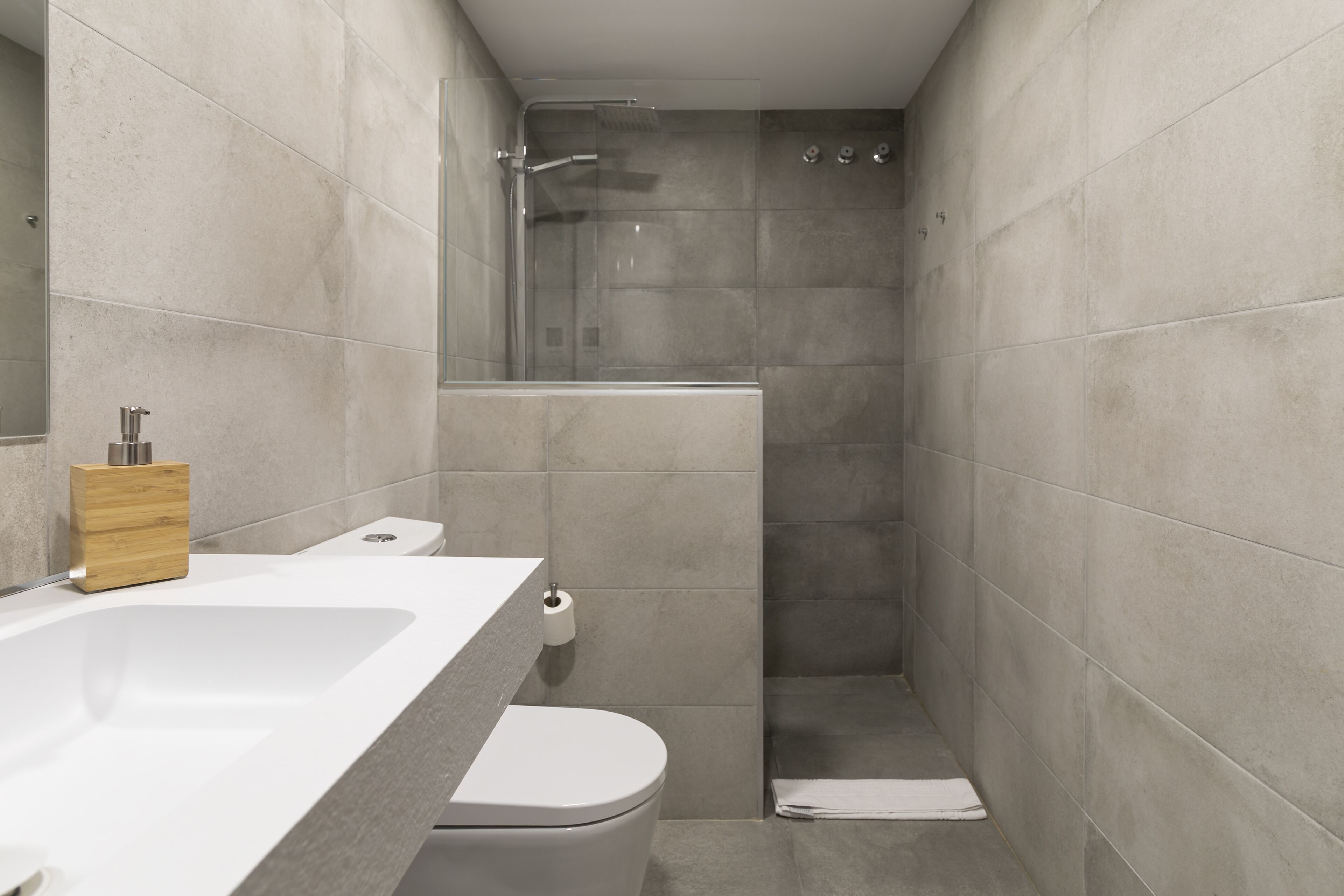 A modern bathroom with a shower, toilet, and sink.