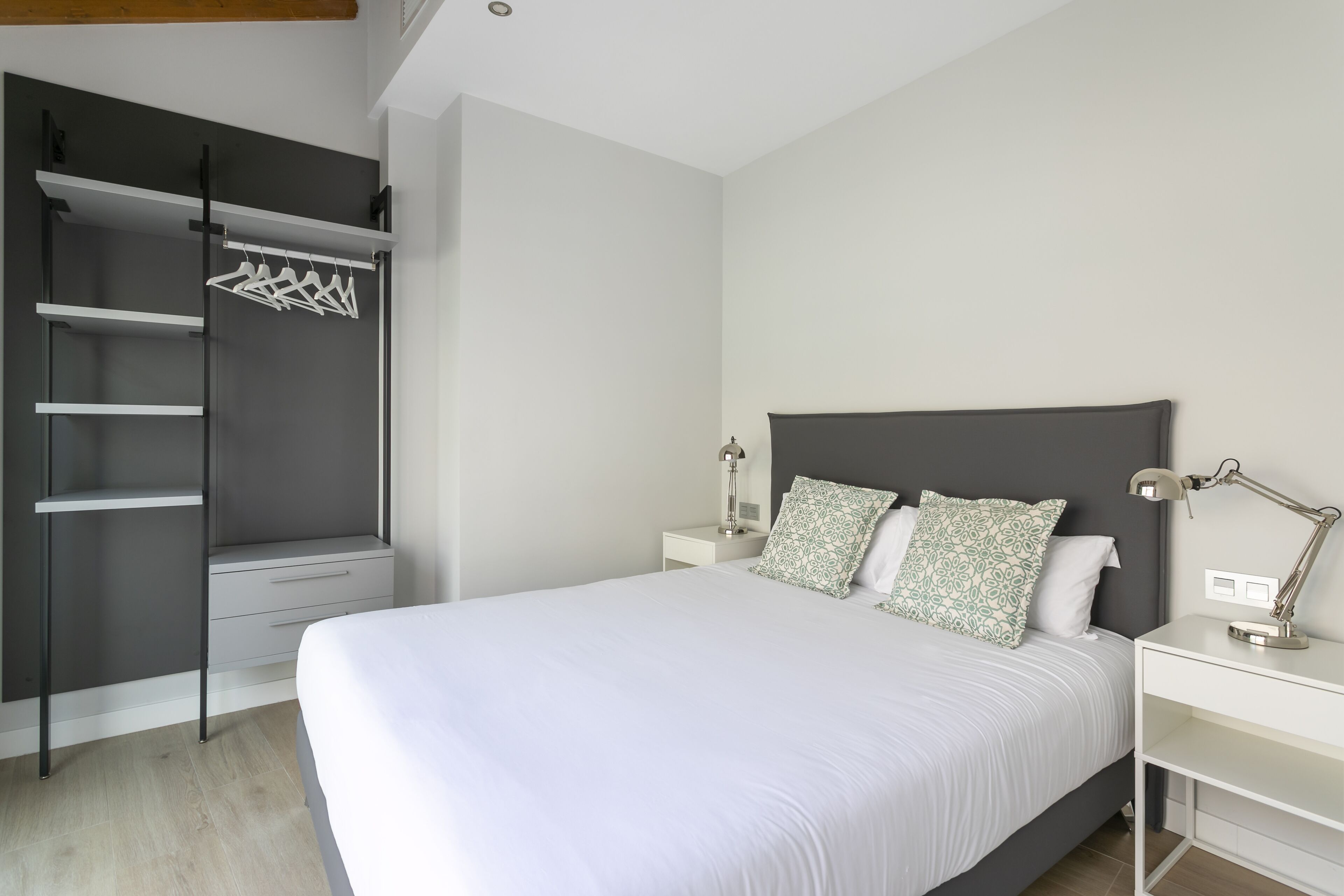 A bedroom with a bed, a wardrobe, a nightstand, and a desk.