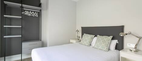 A bedroom with a bed, a wardrobe, a nightstand, and a desk.