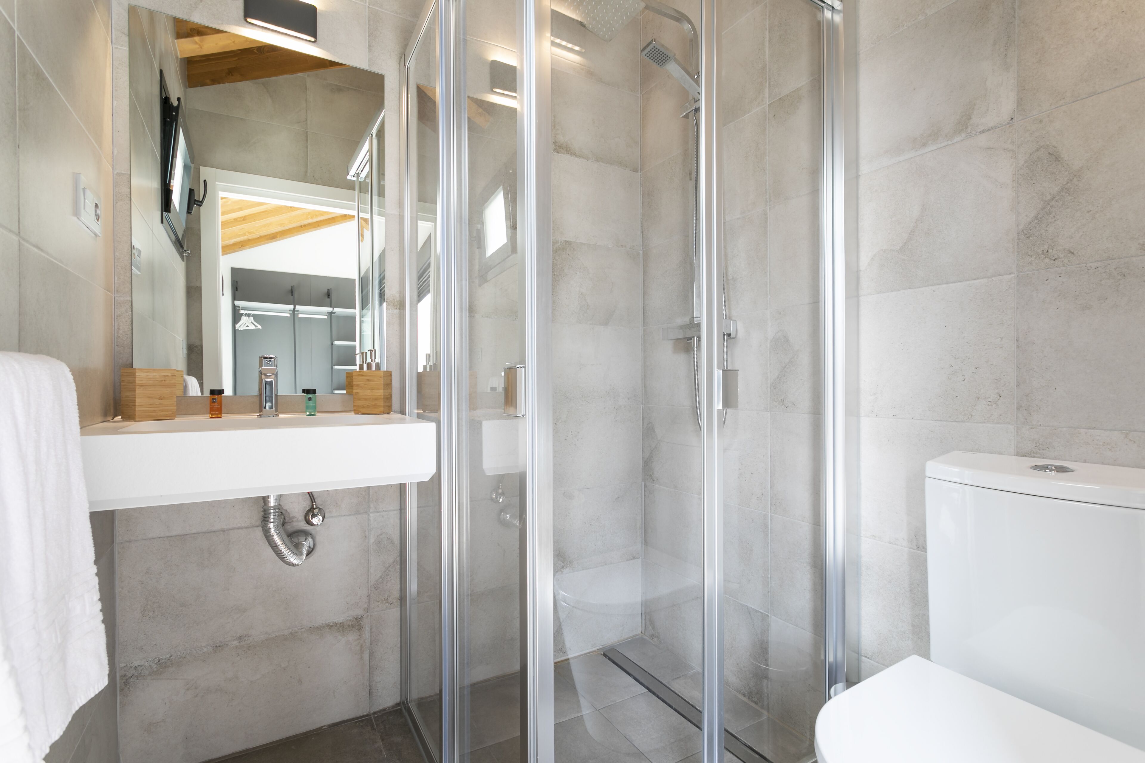 Een moderne badkamer met een douchecabine, een wit wastafelmeubel met een spiegel erboven en een toilet.