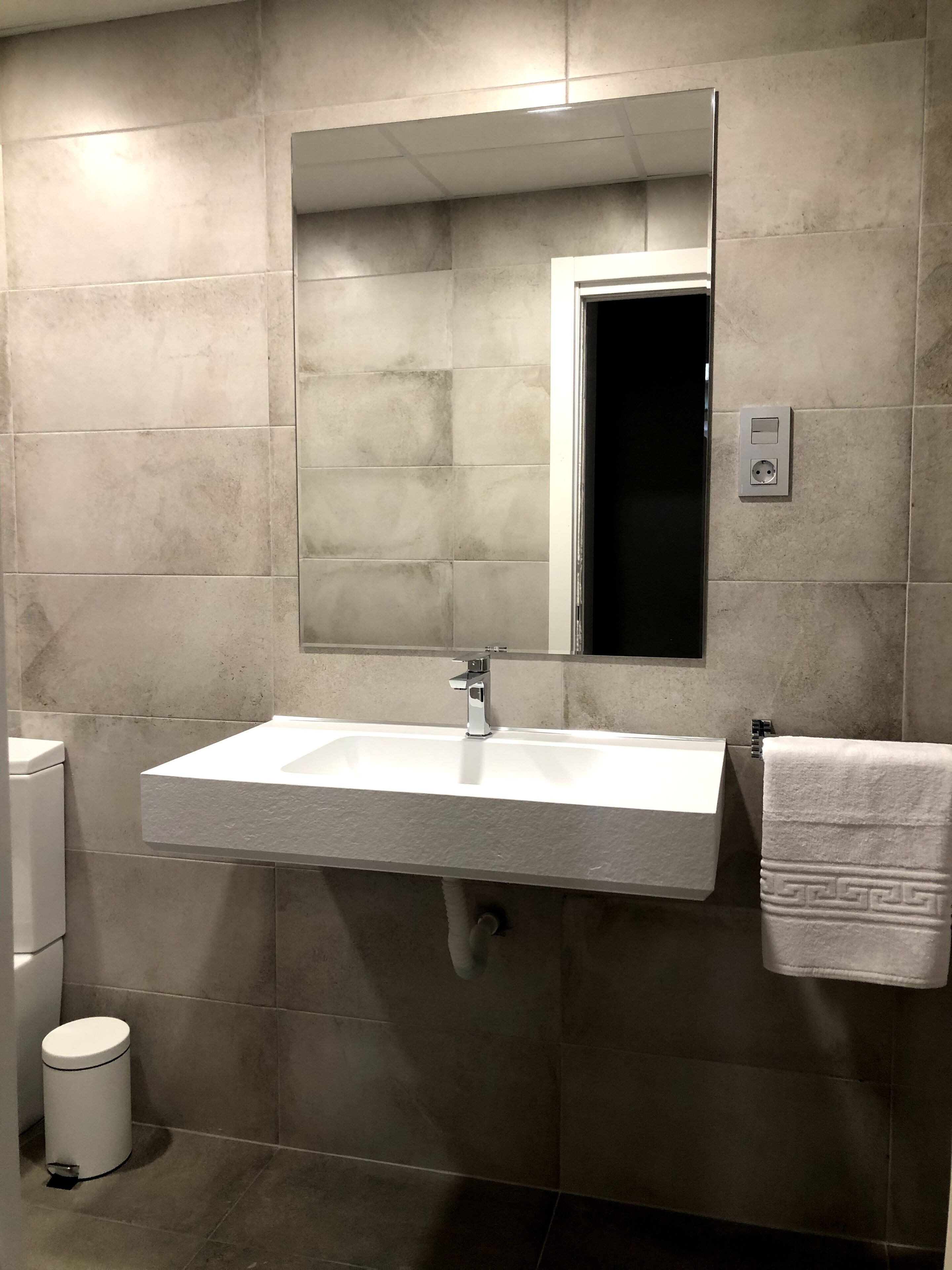 A bathroom with a white sink, a mirror, and a towel hanging on the wall.