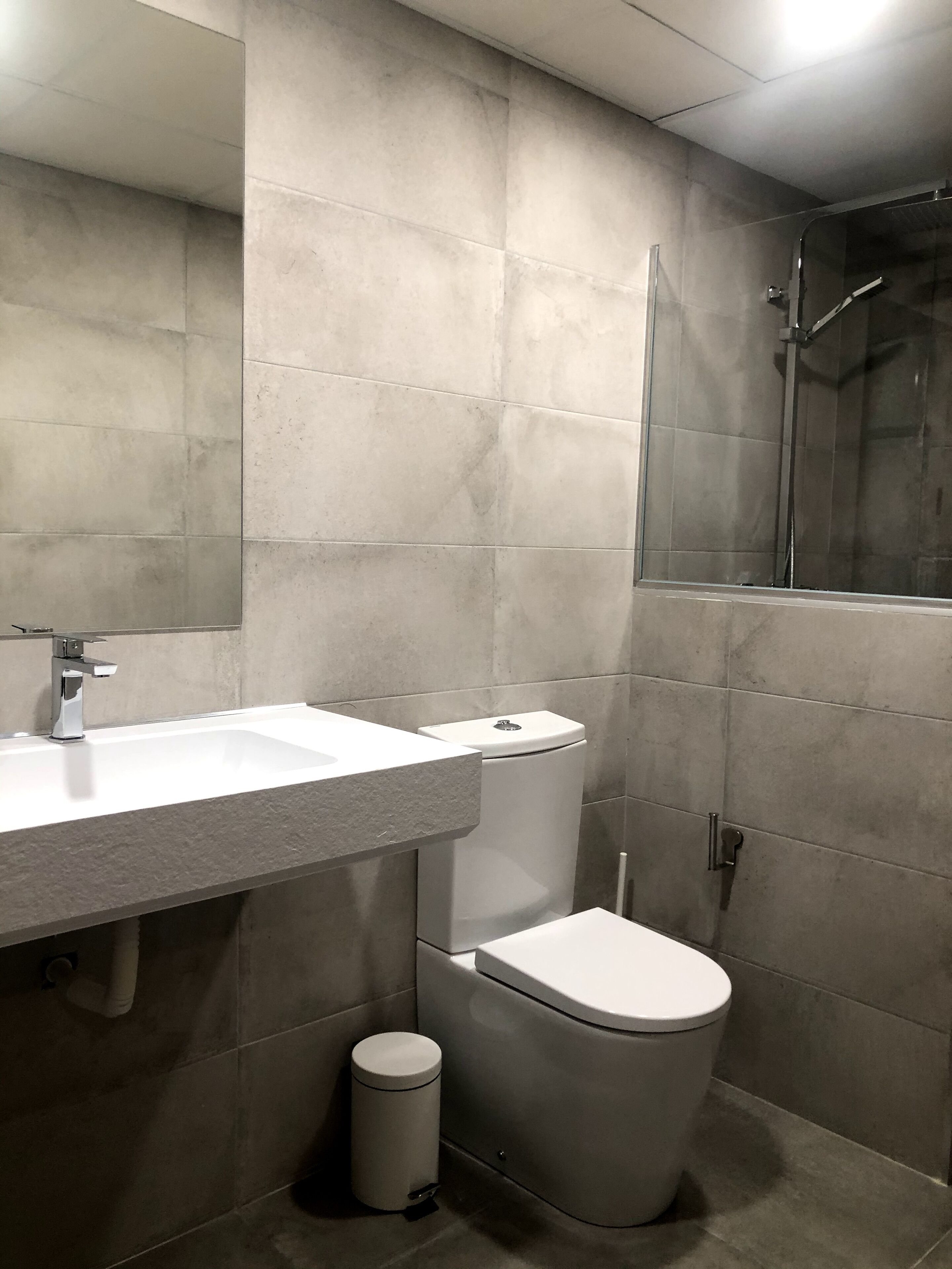 A modern bathroom with a white sink, toilet, and shower.