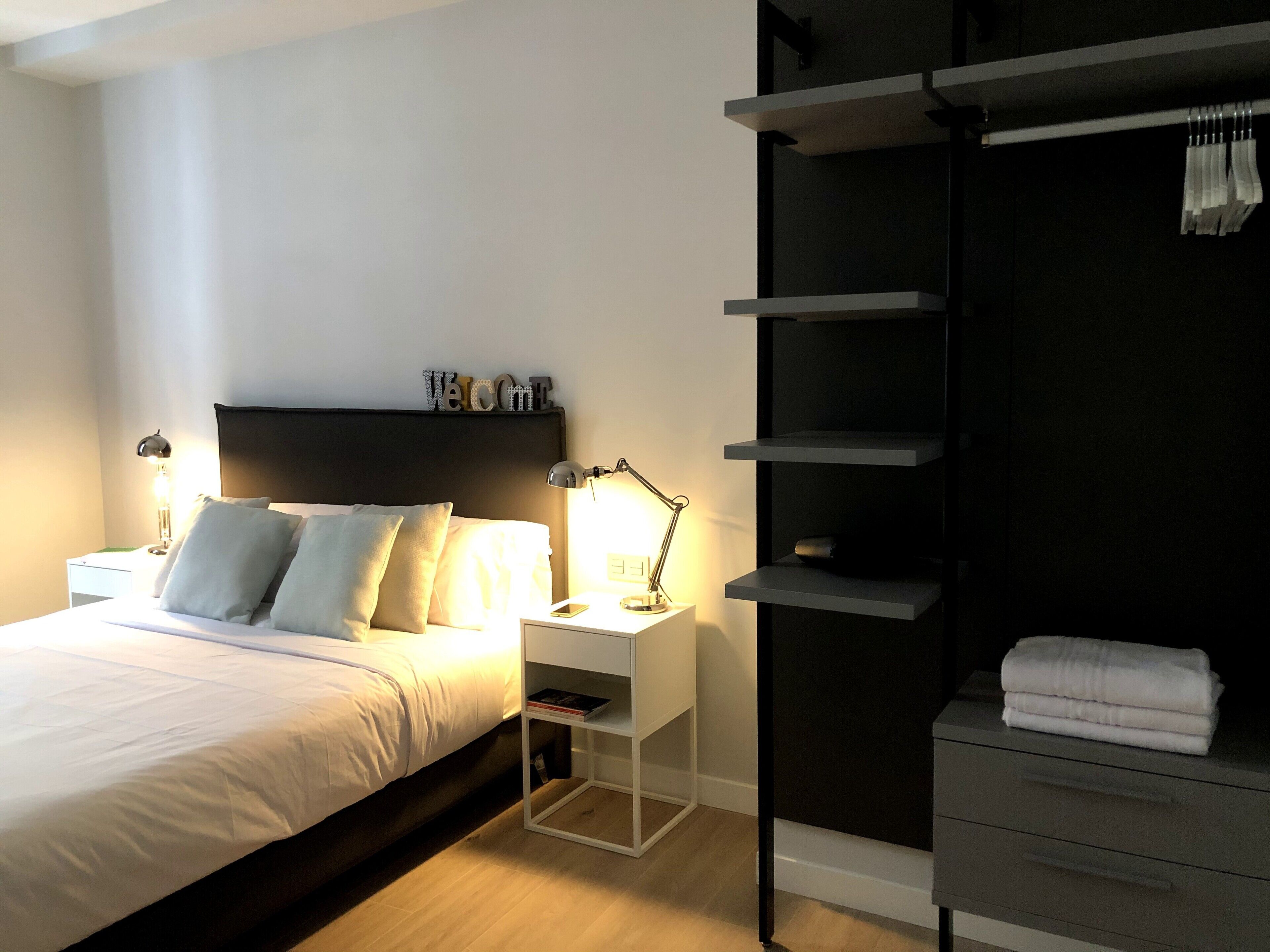 A modern bedroom with a bed, bedside lamps, a nightstand, and a built-in wardrobe.