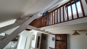 A spacious living area with a high ceiling, a wooden staircase, and a view of the kitchen. - Apartment 37 m² Nuits Saint Georges (Nuits-Saint-Georges)