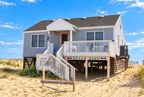 Ein Strandhaus mit Balkon, einem Schild mit der Aufschrift 'BEACH BABY' und der Hausnummer 4509.