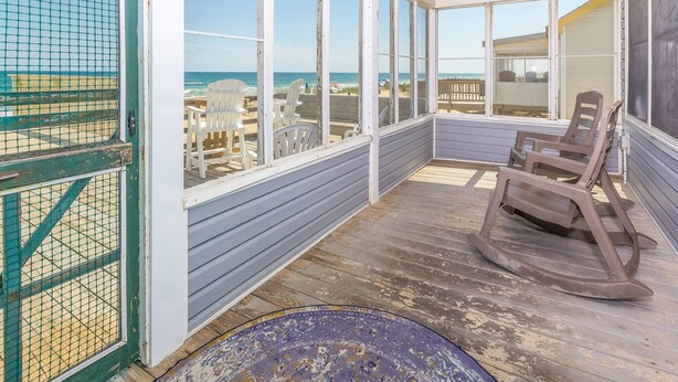 A covered porch with a view of the beach, wooden chairs, and a rocking chair. - Beach Baby - Kitty Hawk MP 2.5, Oceanfront, 3 Bedrooms, Best Views on the OBX, Pets OK (Kitty Hawk)