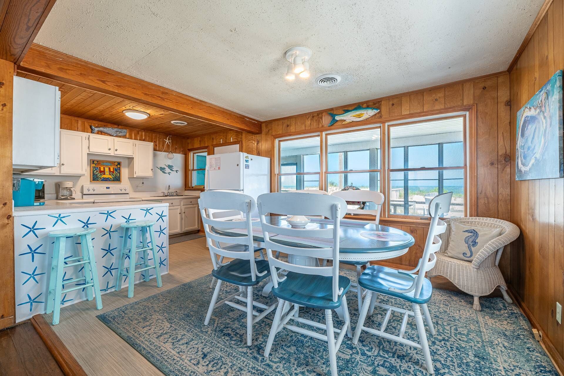 A cozy cabin interior with a kitchen, dining area, and large windows offering a view of the outdoors.