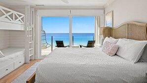 Een slaapkamer met een bed, een plafondventilator en uitzicht op de oceaan.