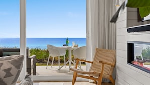 Een balkon met een tafel en stoelen, een rieten stoel, en uitzicht op de oceaan.