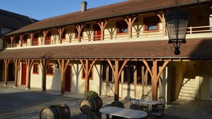 A building with a covered outdoor area, wooden beams, and tables and chairs. - Le Clos Margot (Blancs-Coteaux)
