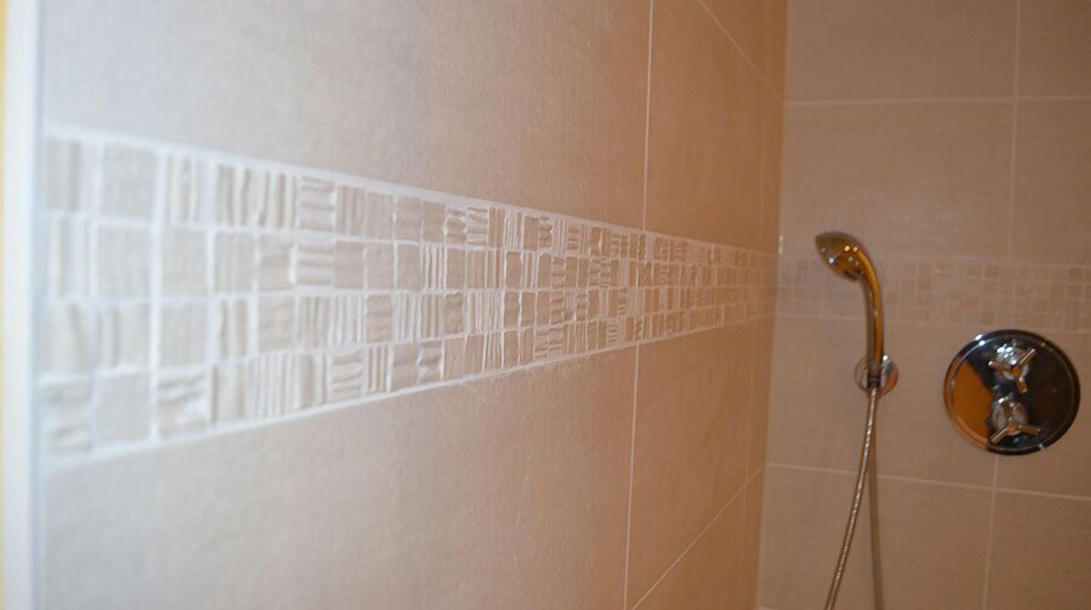 A shower area with a tiled wall and a chrome shower head.