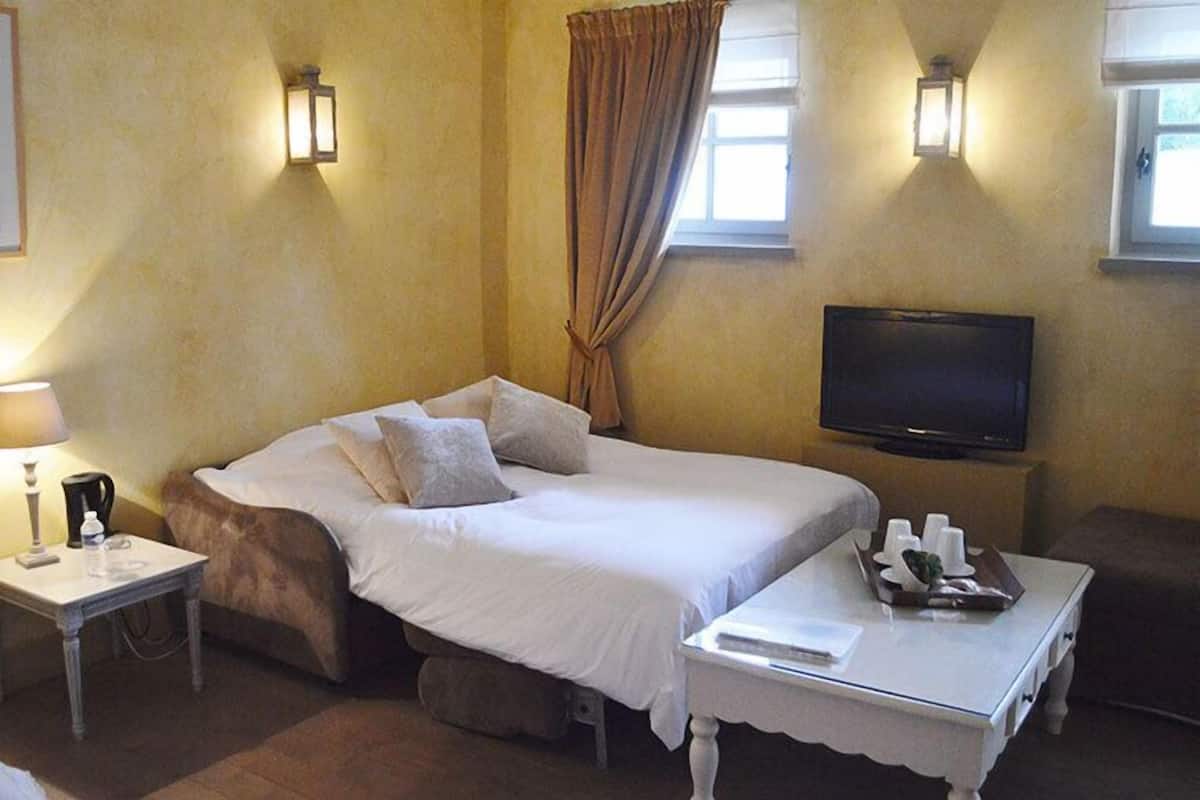 A hotel room with a bed, bedside tables, a television, and a window with curtains.