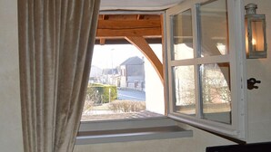 A room with a window overlooking a street, wooden beams, and a lantern. - Le Clos Margot (Blancs-Coteaux)