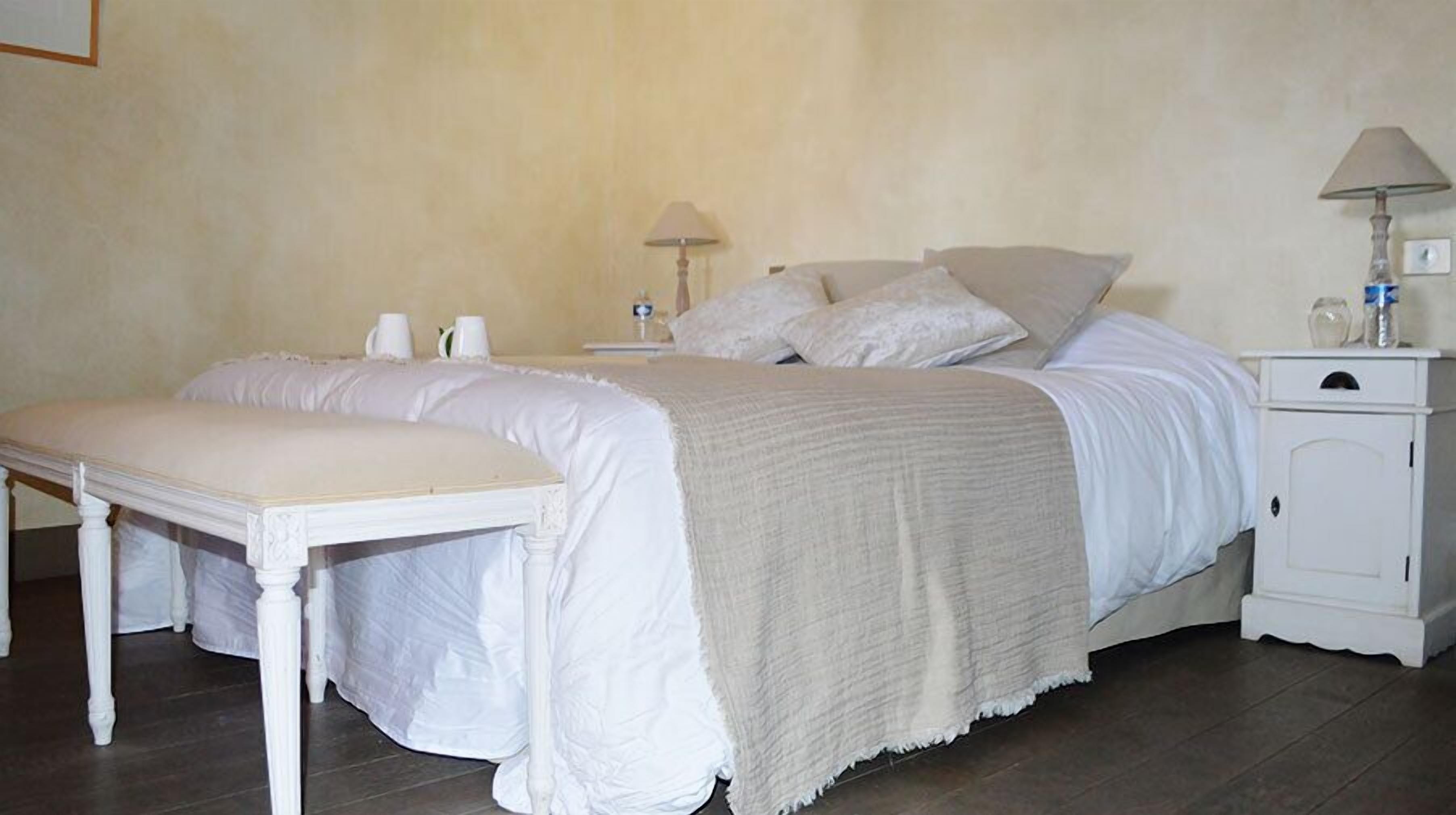 A bedroom with a bed, bedside tables, a bench, and a nightstand.