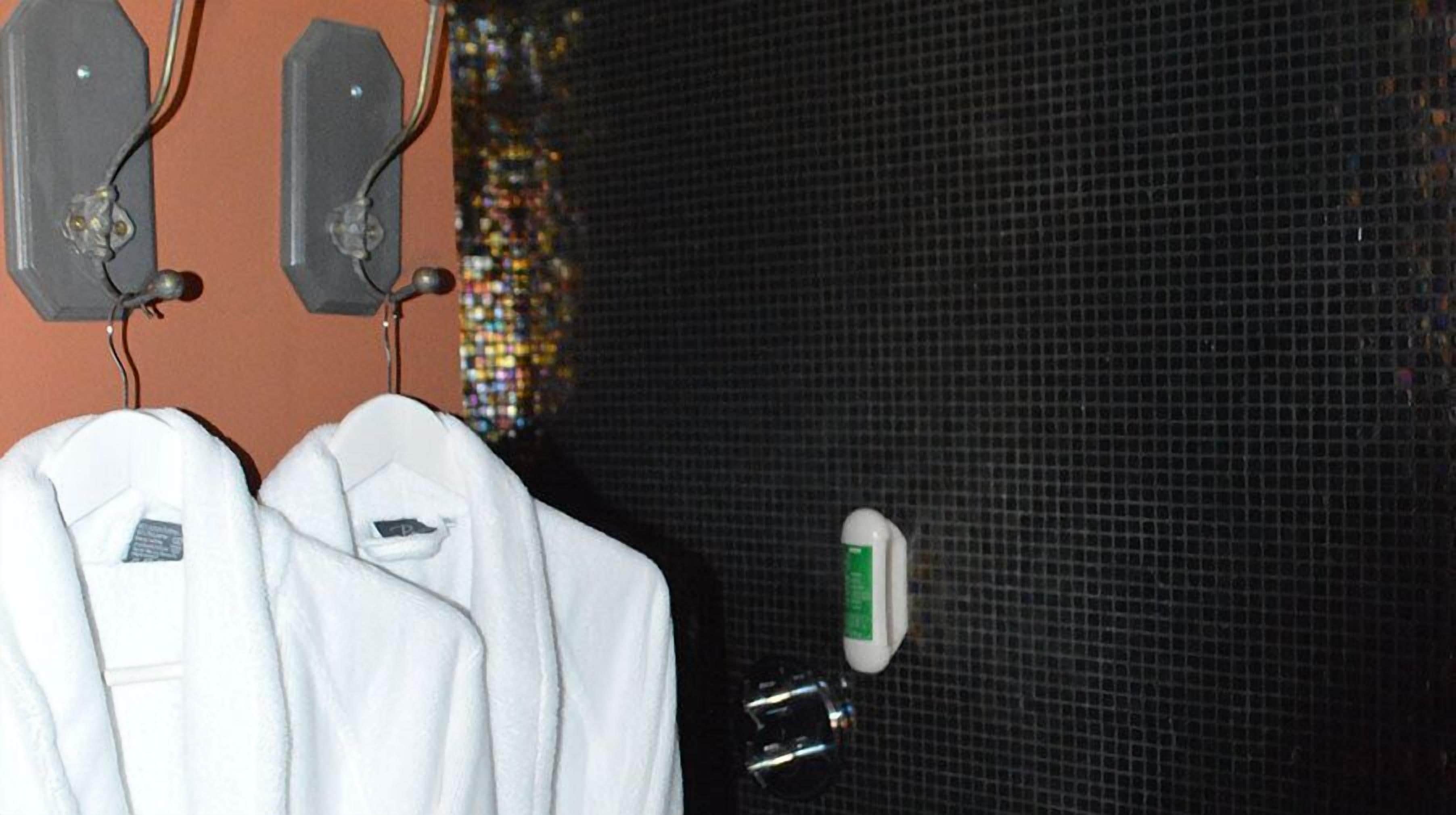 A white robe hanging on a hook, a small bottle, and a speaker on a wall.