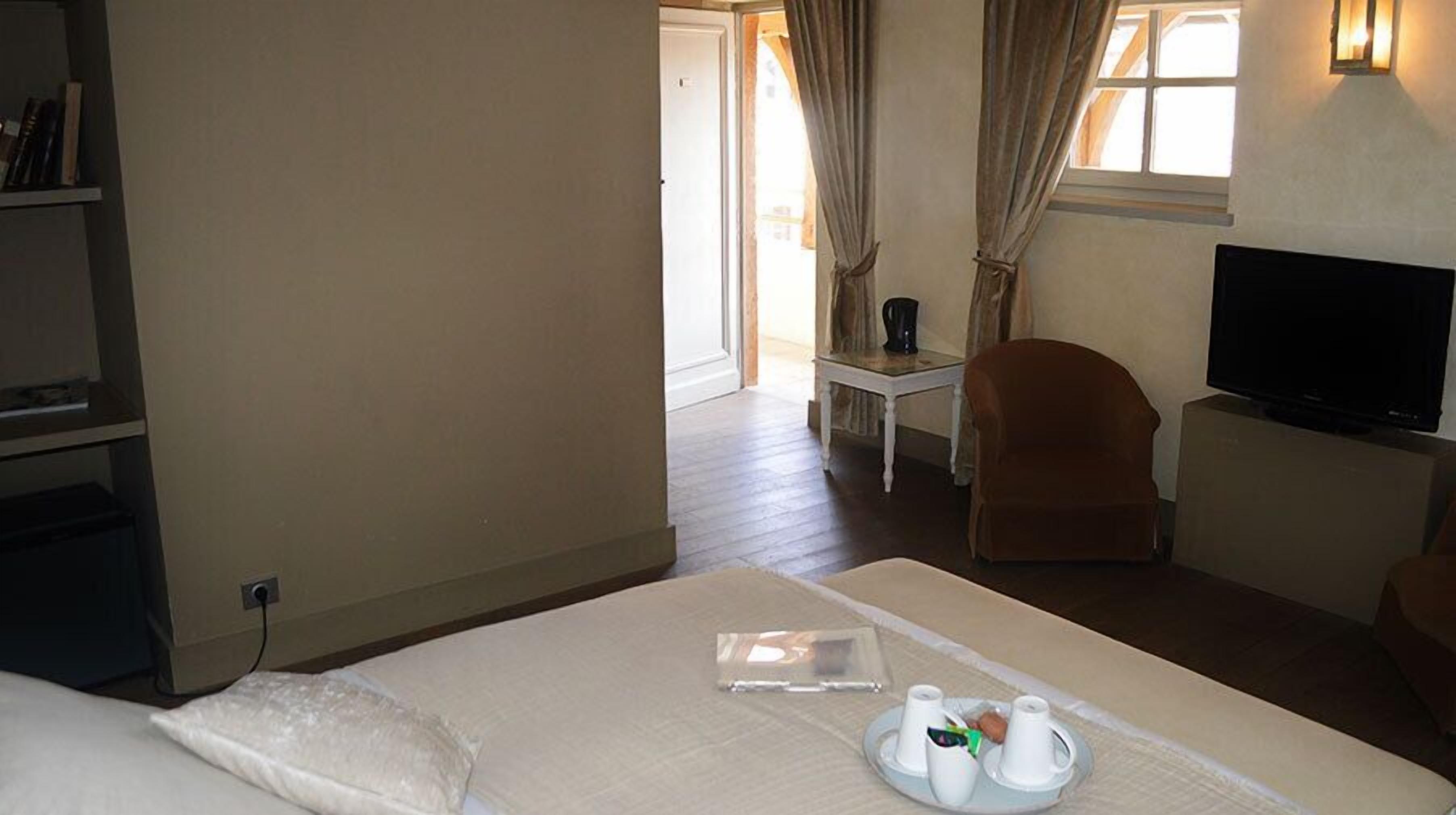 Habitació d'hotel amb un llit, una televisió, una cadira i una taula amb un plat de menjars de l'esmorzar.