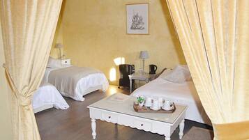 A hotel room with two beds, a small table with a tray of cups and a bottle, and a lamp on a nightstand.