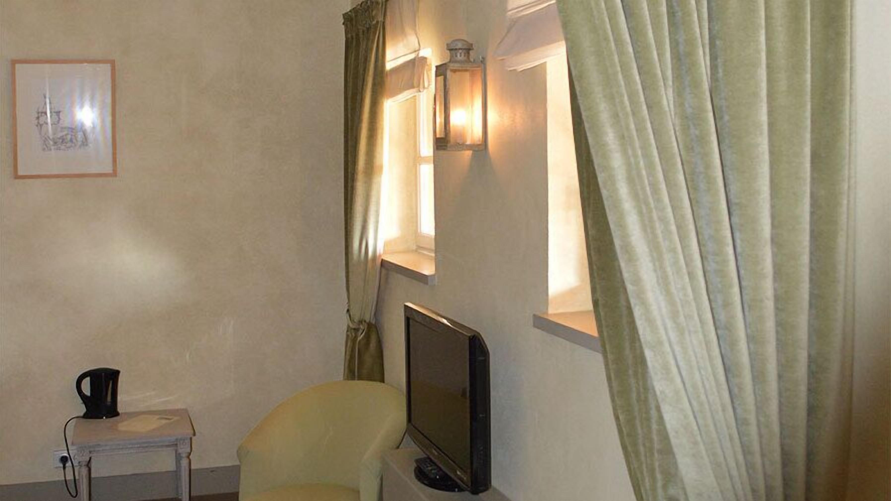 A room with a television, a small table with a kettle, and a framed picture on the wall.
