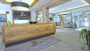 A reception area with a wooden reception desk, stone pillars, and a large chandelier.