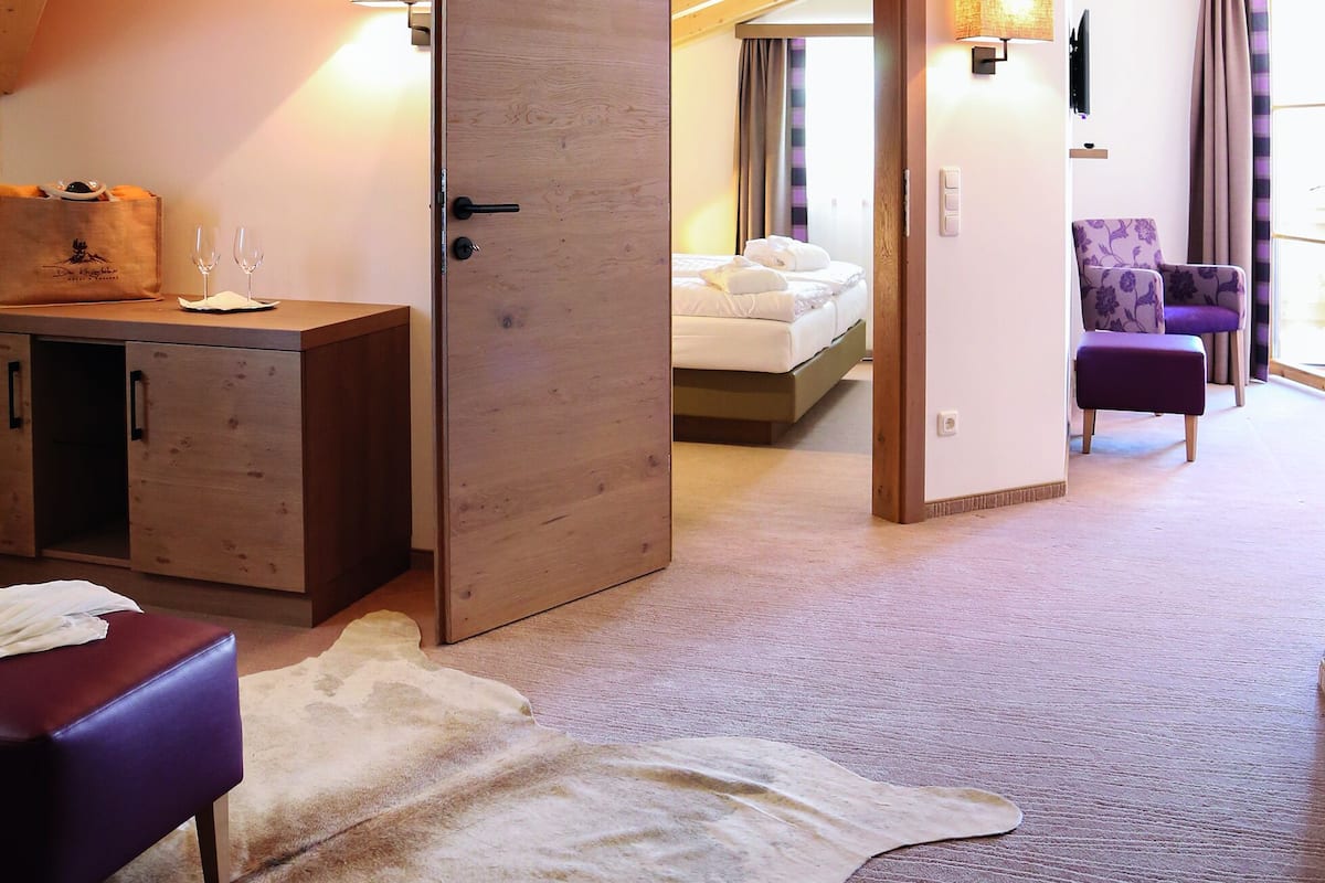 Ein Zimmer mit Holzboden, einem Bett, einem Schreibtisch, einem Stuhl und einem großen Fellteppich.