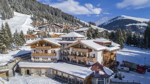 A large, multi-story hotel with a ski slope in the background.