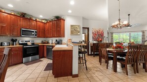 A spacious kitchen with wooden cabinets, a central island, and a dining area with a chandelier. - Reflection Retreat - A quiet Oasis by Table Rock Lake. Come and relax! (Hollister)