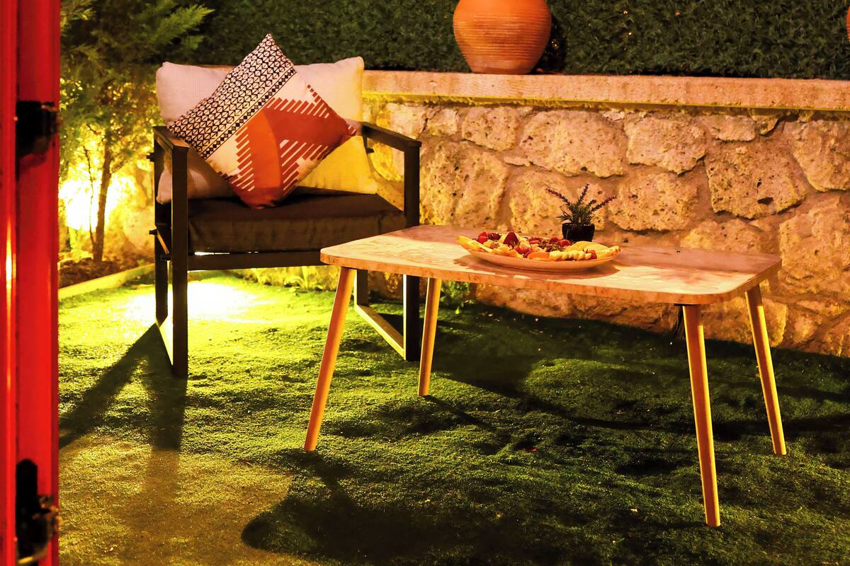 Un espace extérieur accueillant, avec un mur en pierre, une table en bois et une chaise rembourrée.