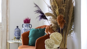A cozy living room with a brown leather sofa, a teal pillow, and a glass table with decorative items. - Alacati Lulja Hotel (Cesme)