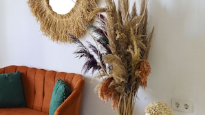 A room with a sofa, a vase with dried plants, and a bust on a small table. - Alacati Lulja Hotel (Cesme)