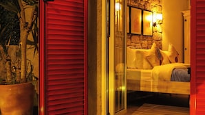 A cozy bedroom with a bed, a nightstand, and a potted plant. - Alacati Lulja Hotel (Cesme)