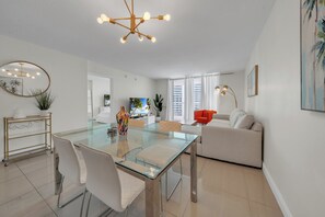 Ein modernes Wohnzimmer mit einem Glastisch, weißen Sofas und einem großen Spiegel.