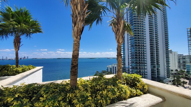 A high-rise building with a view of the sea and other buildings in the background.
