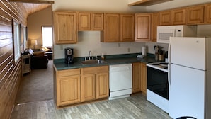 A kitchen with wooden cabinets, a dishwasher, a microwave, and a refrigerator. - Lake Front Rental/Downtown Grand Lake
Apt 3 The Falcon (Grand Lake)
