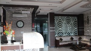 Zona de recepción con mostrador, un reloj, pared con diseño y un sofá.