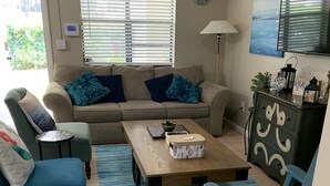 Una sala de estar con un sofá, sillones, una mesa de centro y un televisor.