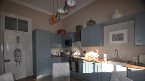 A modern kitchen with light blue cabinets, a central island, and pendant lighting. - Carnell Private Apartment (Hurllford)