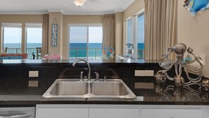 A kitchen with a large island, a double sink, and a view of the ocean. - Treasure Island 0412 (Panama City Beach)