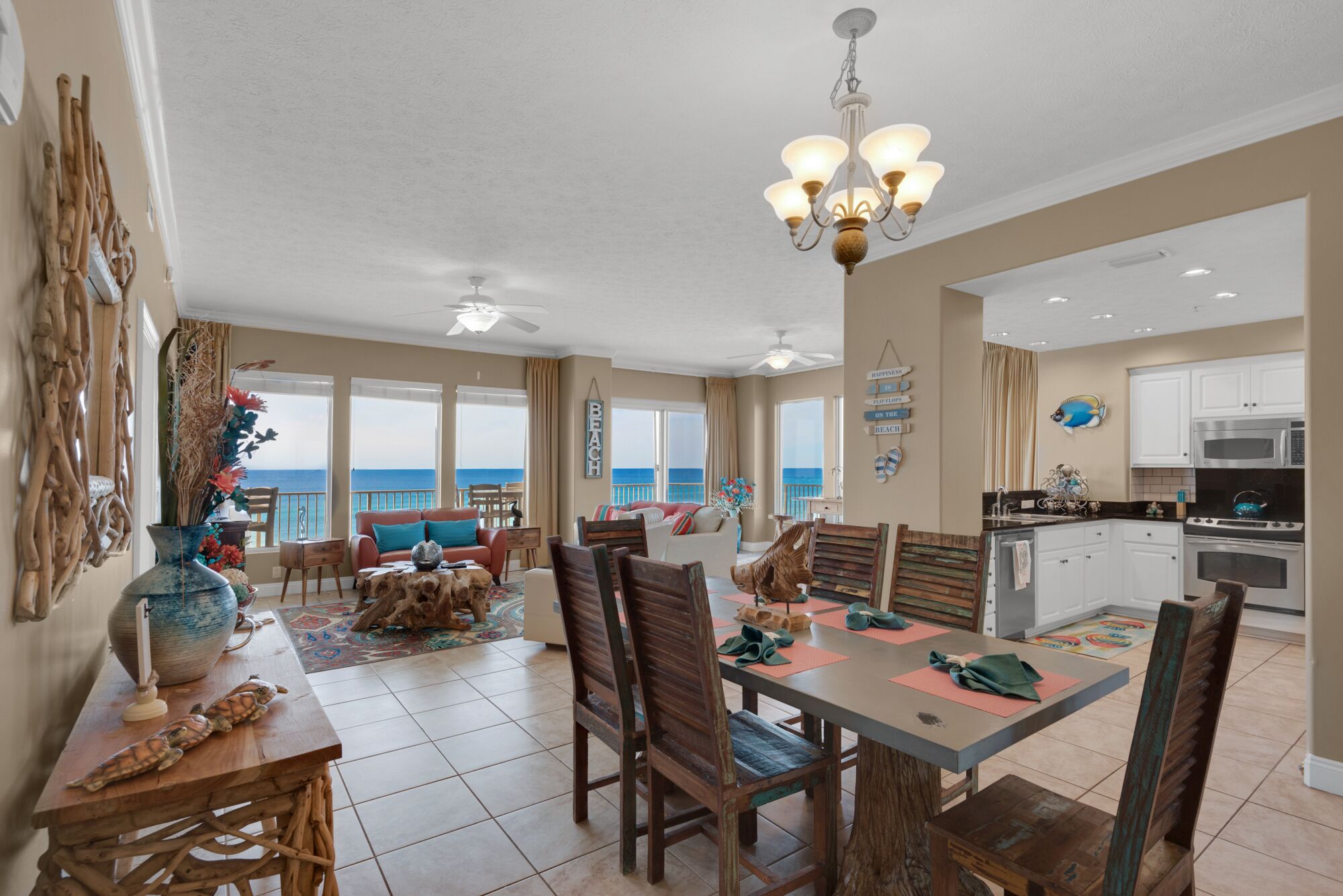 A spacious living area with a view of the ocean, a dining table with chairs, a kitchen area, and a ceiling fan.