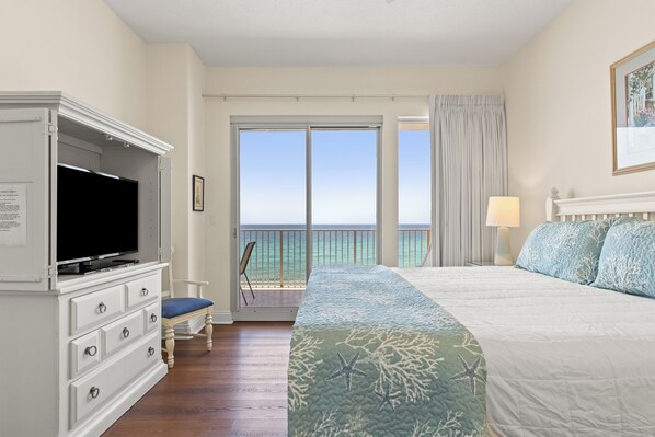 A hotel room with a bed, a television, a desk, and a view of the ocean. - Treasure Island 0503 (Panama City Beach)